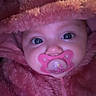 Alaina is registered to the contest to win money with this photo: baby, pacifier, pink, hat, fluffy, close_up, face, child, cute, infant, warm_clothing, portrait, eyes, cozy, soft_texture, headwear, sucking, young_child, person, adorable