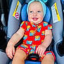baby, child, car_seat, headband, bow, red_outfit, french_fries_pattern, smile, happy, infant, sitting, blue_cushion, clothing, cute, portrait, seatbelt, indoor, person, skin, face