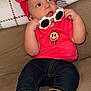 Oaklynn is registered to the contest to win money with this photo: baby, child, headband, red_bow, sunglasses, flower_shaped, shirt, red_shirt, denim_pants, rolled_up_jeans, barefoot, couch, blanket, plaid_blanket, indoor, cute, curious, portrait, sitting, infant