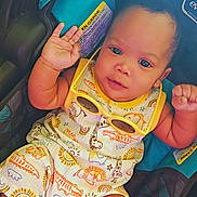 Mckayden joined the competition — help win amazing prizes! baby, child, infant, car_seat, romper, yellow_sunglasses, waving_hand, patterned_clothing, barefoot, cute, smiling, indoor, seatbelt, colorful, person, portrait, young_child, happy, casual, comfort