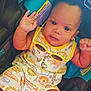 baby, child, infant, car_seat, romper, yellow_sunglasses, waving_hand, patterned_clothing, barefoot, cute, smiling, indoor, seatbelt, colorful, person, portrait, young_child, happy, casual, comfort