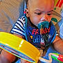 Mckayden is registered to the contest to win money with this photo: baby, baby_seat, bib, child, closeup, colorful, curly_hair, cute, face, focus, foot, hand, happy, indoor, infant, pacifier, person, playful, striped_clothing, toy