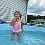 child, girl, swimsuit, pool, water, summer, outdoor, backyard, house, sky, clouds, playful, happy, water_ripples, siding, daytime, person, cute, fun, smiling