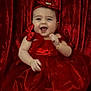 baby, child, red_dress, headband, smiling, happy, portrait, indoor, tulle, bow, jewelry, bracelet, infant, celebration, cute, person, fabric, red_background, festive, sitting