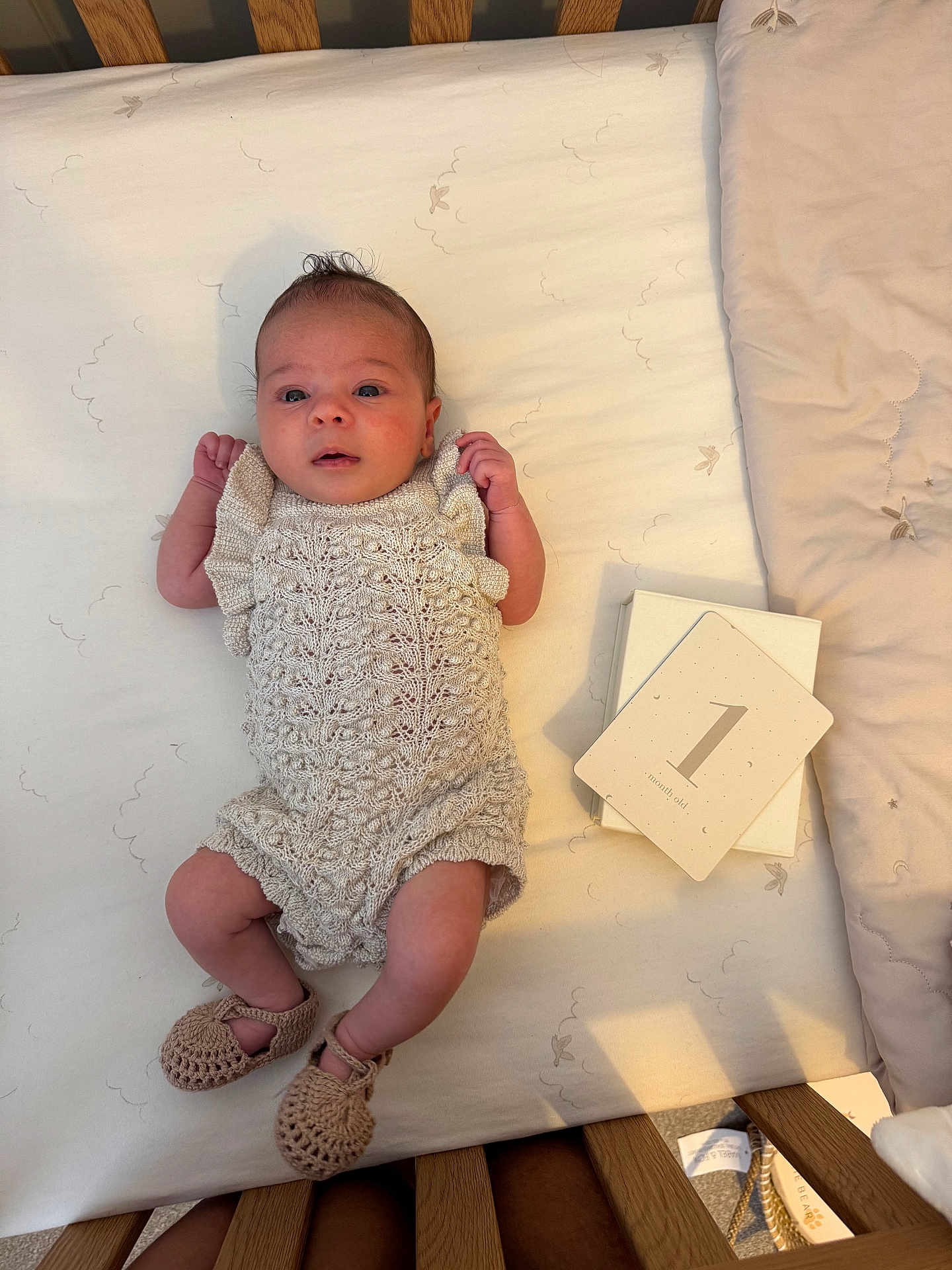 Arella joined the competition — help win amazing prizes! baby, infant, crib, knitted_outfit, booties, milestone_card, one_month_old, soft_bedding, wooden_crib, lying_down, newborn, cute, portrait, indoors, peaceful, small_hands, small_feet, blanket, calm, baby_girl