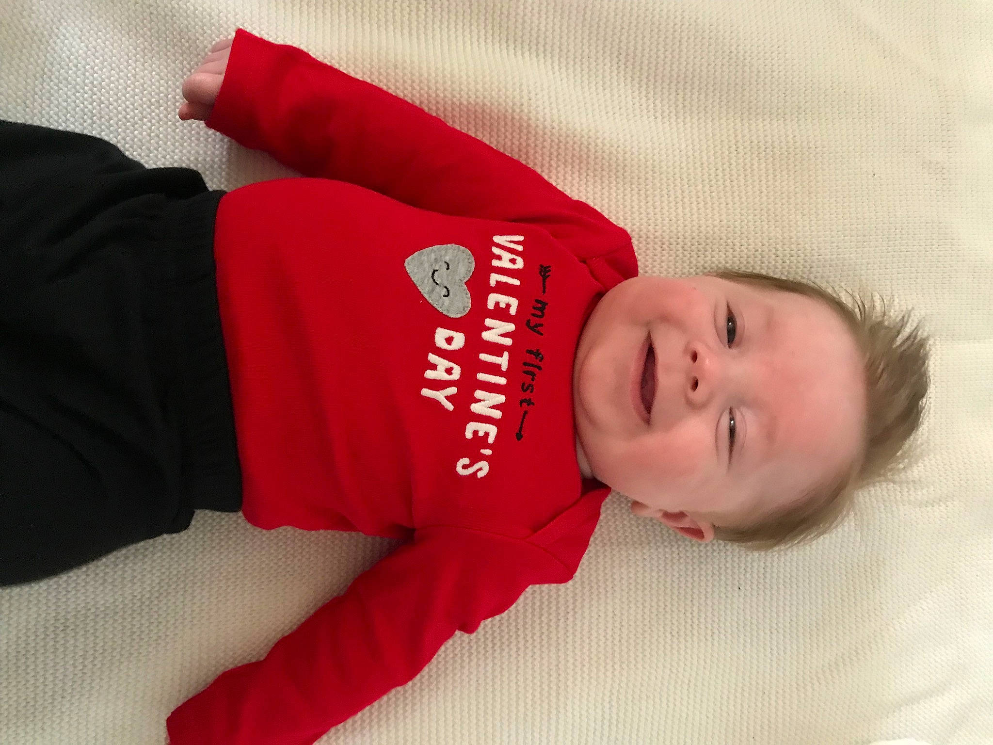 Bodhi is registered to the contest to win money with this photo: arm, baby, baby_toddler_clothing, carmine, child, comfort, elbow, facial_expression, font, happy, hat, human_body, knee, mammal, pattern, person, skin, sleeve, smile, t_shirt