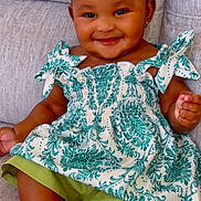 Kalia joined the competition — help win amazing prizes! baby, child, smiling, sitting, headband, bow, dress, floral_pattern, green_shorts, white_shoes, couch, indoors, happy, cute, portrait, skin, face, hands, feet, infant