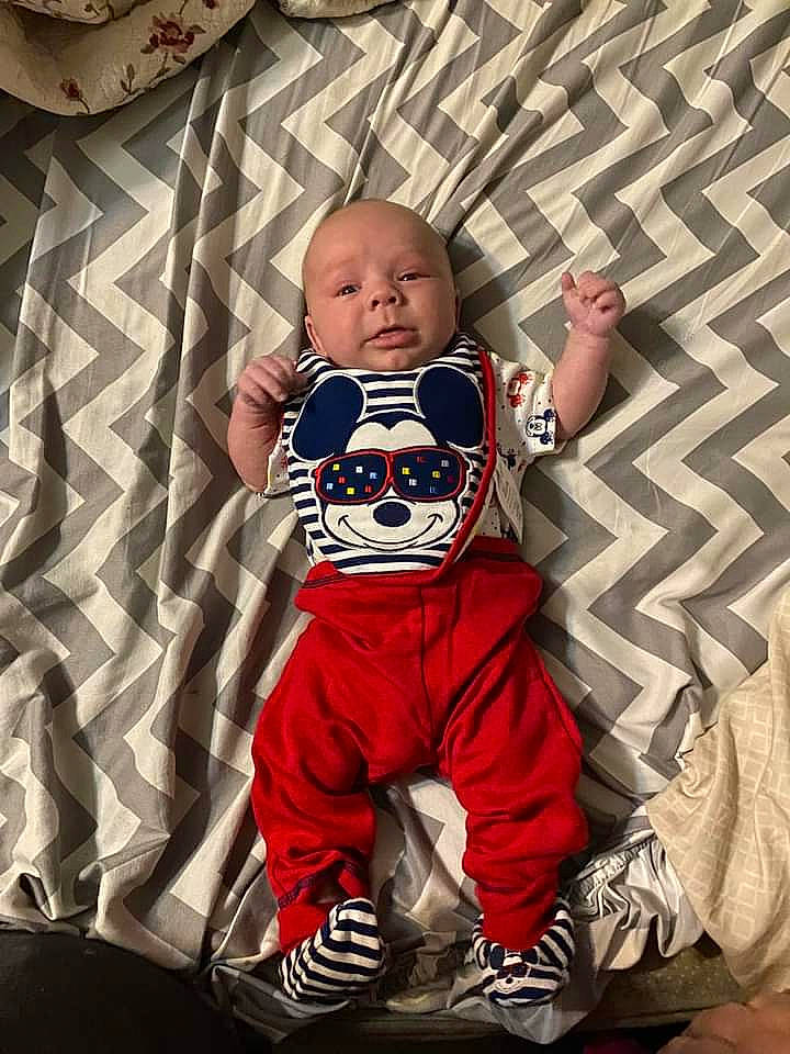 Anakin is registered to the contest to win money with this photo: baby, baby_toddler_clothing, carmine, child, comfort, cool, eye, flash_photography, flooring, happy, head, human, linens, pattern, person, personal_protective_equipment, product, sleeve, t_shirt, textile