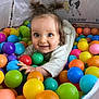 toddler, child, ball_pit, colorful_balls, playtime, happy, smiling, pigtails, indoor, cute, portrait, fun, toy, plastic_balls, crawling, play_area, bright_colors, young_child, joyful, cartoon_background