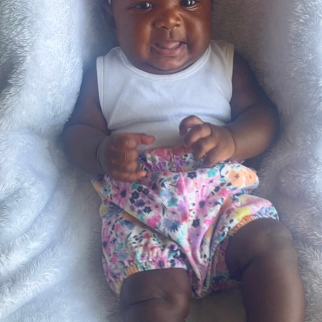 Amarah-Jàe is registered to the contest to win money with this photo: baby, child, chubby_legs, closeup, cute, floral_shorts, fluffy_blanket, happy, headband, indoor, infant, lying_down, pink_bow, portrait, relaxed, skin, smiling, soft_texture, tongue_out, white_top