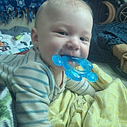 Feilan is registered to the contest to win money with this photo: baby, child, teething_toy, blue, striped_clothing, blanket, bed, indoor, cute, face, smiling, hand, comfort, tapestry, decor, person, portrait, infant, young_child, soft