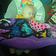 Feilan is registered to the contest to win money with this photo: baby, infant, sleeping, car_seat, blanket, fan, toy_monkey, indoors, portrait, colorful_blanket, cozy, child, nap, seatbelt_label, socks, floor, pajamas, soft_toys, bedding, peaceful