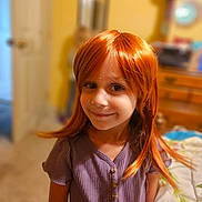 Kory-Lynne joined the competition — help win amazing prizes! child, girl, smiling, portrait, red_hair, ginger_hair, long_hair, indoor, bedroom, warm_lighting, purple_shirt, standing, face, eyes, nose, mouth, furniture, bed, dresser, photography