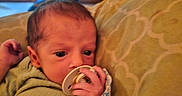 Ricky joined the competition — help win amazing prizes! baby, infant, child, portrait, pacifier, blanket, bib, bed, pillow, indoors, bedroom, sitting, lying_down, face, eyes, hair, clothing, cozy, home, daylight