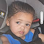 toddler, child, car_seat, seatbelt, blue_clothing, person, face, hair, eyes, skin, expression, safety, vehicle_interior, shoulder, young_child, portrait, indoors, straps, closeup, cute