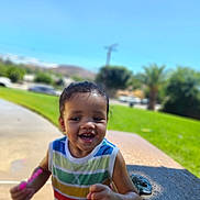 Amilliana is registered to the contest to win money with this photo: toddler, child, smiling, outdoor, daylight, grass, sky, bubble, toy, playing, happy, colorful_clothing, tank_top, wet_hair, person, park, concrete, bench, sunny, nature