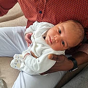 Liam a rejoint le concours — aidez-le/la à gagner de superbes lots ! baby, adult, holding, couch, clothing, white_outfit, socks, face, portrait, indoor, person, hand, watch, seated, expression, looking_up, skin, fabric, comfort, casual