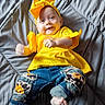 baby, barefoot, casual_clothing, child, colorful, cute, happy, headband, indoor, infant, jeans, lying_down, patches, playful, portrait, quilted_blanket, small_feet, smile, yellow_clothing, young_child