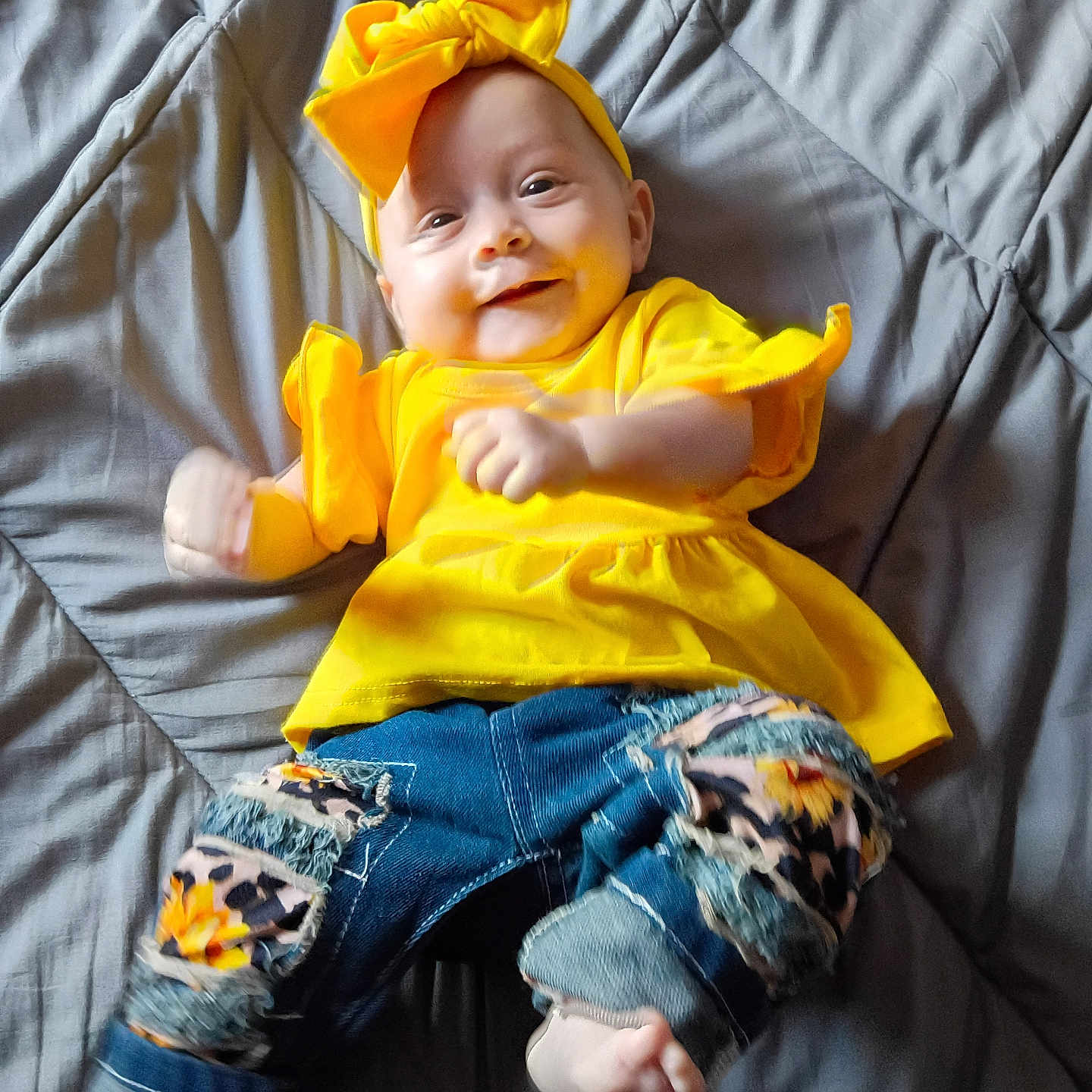 Jaimalyn is registered to the contest to win money with this photo: baby, barefoot, casual_clothing, child, colorful, cute, happy, headband, indoor, infant, jeans, lying_down, patches, playful, portrait, quilted_blanket, small_feet, smile, yellow_clothing, young_child