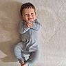 baby, infant, child, onesie, smile, hands, feet, lying_down, blue_clothing, soft_texture, face, happy, cute, portrait, human, young_child, indoors, skin, head, expression