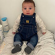 Maylonn participe au concours pour gagner de l'argent avec cette photo : baby, denim_overalls, socks, blanket, infant, clothing, face, person, cute, indoor, expression, hair, child, sitting, blue_eyes, soft_toys, baby_care, bottle, white_background, curious