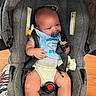 baby, bib, blue, calm, car_seat, casual, child, closeup, clothing, cute, footwear, gray, indoor, infant, pacifier, person, seatbelt, sitting, wood_floor, yellow