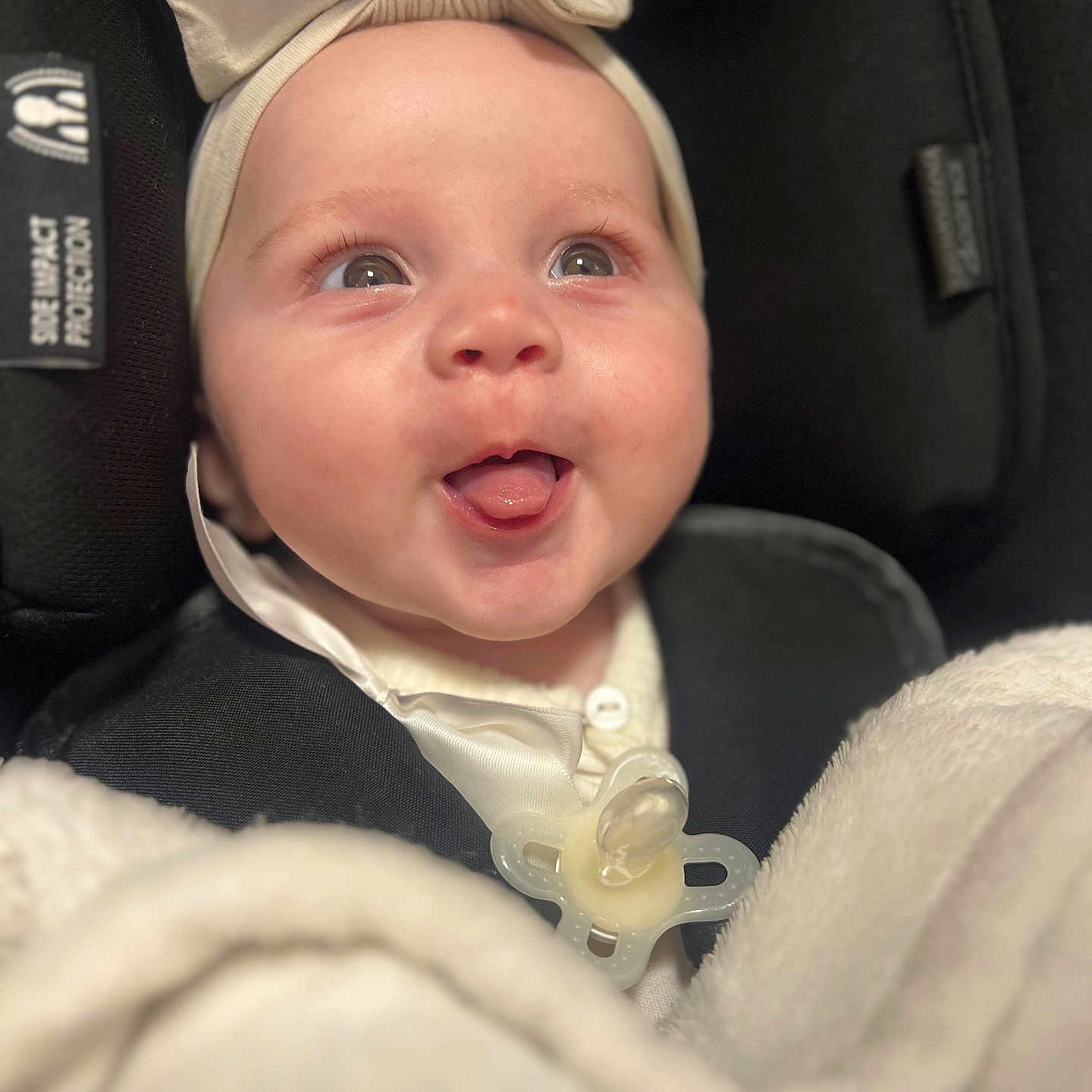 Aria joined the competition — help win amazing prizes! baby, baby_accessory, blanket, bow, car_seat, child, closeup, clothing, comfort, cute, face, happy, headwear, indoors, infant, pacifier, person, seatbelt, smiling, soft_texture