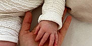Louis participe au concours pour gagner de l'argent avec cette photo : baby, hand, adult_hand, skin, texture, knitwear, white_clothing, closeup, touch, connection, soft, fabric, resting, fingers, palm, delicate, contrast, beige, comfort, intimacy