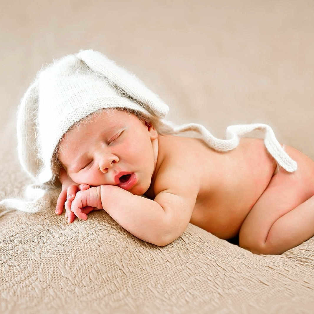 Louis participe au concours pour gagner de l'argent avec cette photo : baby, beige, blanket, closed_eyes, cute, face, hand, hat, headwear, infant, knitted_hat, lying_down, newborn, peaceful, portrait, resting, skin, sleeping, soft_texture, toddler