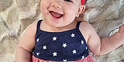Maeve joined the competition — help win amazing prizes! baby, blanket, blue, cheerful, child, cute, dress, face, happy, headband, indoors, infant, lying_down, red, skin, smiling, soft, stars, striped, toy