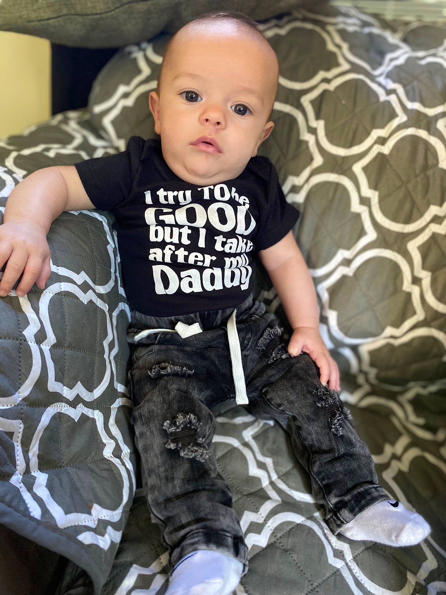 David is registered to the contest to win money with this photo: baby, baby_toddler_clothing, child, comfort, cool, face, fashion_design, flash_photography, happy, human_leg, joint, knee, pattern, person, sitting, sleeve, sock, t_shirt, textile, thigh