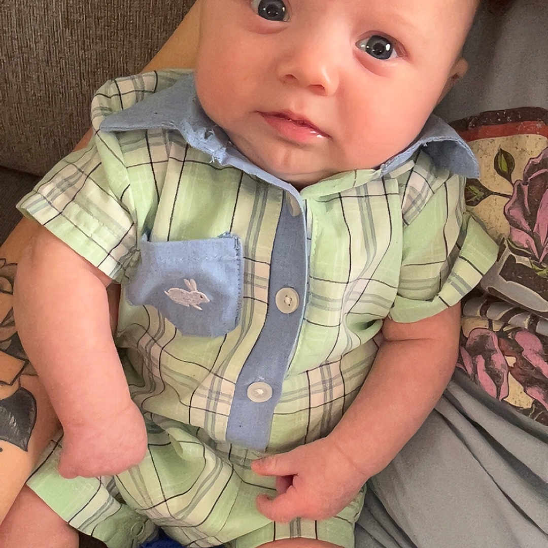 Zayden joined the competition — help win amazing prizes! baby, clothing, couch, cushion, face, furniture, head, homedecor, jeans, newborn, pants, person, photography, portrait, shirt, shorts, sitting, skin, t_shirt, tattoo