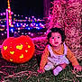 toddler, child, pumpkin, carved_pumpkin, grass, hay, night, string_lights, colorful_lights, festival, outdoor, cute, smiling, sitting, clothing, face, head, celebration, autumn, festive