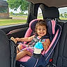 Luna is registered to the contest to win money with this photo: toddler, child, car_seat, sippy_cup, snack, smile, car_interior, seatbelt, clothing, window, tree, road, daylight, safety, person, happy, hair, pink, blue, seat