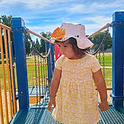 Luna joined the competition — help win amazing prizes! child, girl, playground, bridge, hat, yellow_dress, outdoor, sunny, blue_sky, clouds, chains, metal_platform, curious, summer, trees, grass, park, daylight, casual_clothing, person