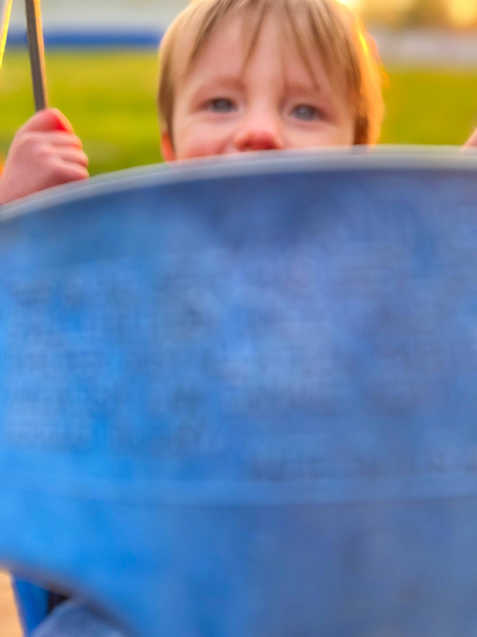 Carter is registered to the contest to win money with this photo: blond, blue, child, city, electric_blue, facial_expression, fun, gesture, grass, happy, leisure, outdoor_play_equipment, people_in_nature, person, play, portrait_photography, recreation, sitting, swing, t_shirt