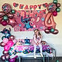 Ambre a rejoint le concours — aidez-le/la à gagner de superbes lots ! child, birthday_party, balloons, cake, table, decoration, pink, blue, celebration, girl, party_hat, smile, wall, floor, banner, chair, cup, drink, tights, dress
