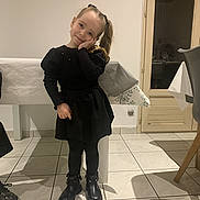 Ambre participe au concours pour gagner de l'argent avec cette photo : child, girl, black_dress, boots, indoor, smile, pose, long_hair, tile_floor, table, chair, door, hand_on_face, cute, floor, wall, home, young, fashion, happy
