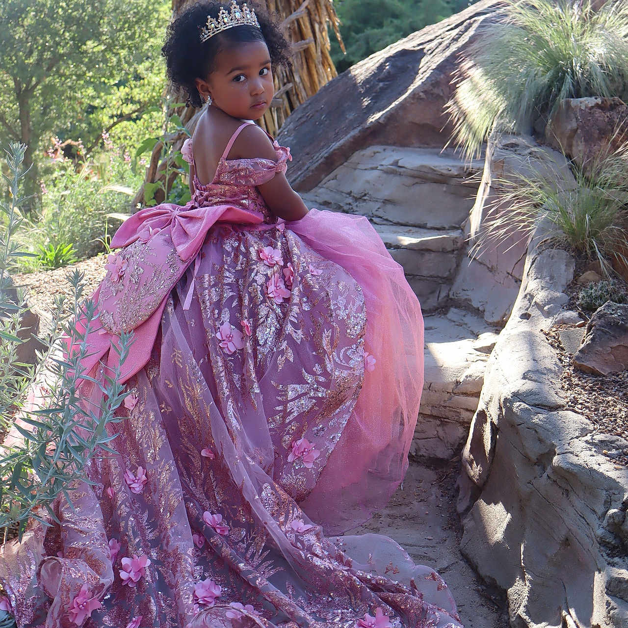 Romina joined the competition — help win amazing prizes! child, costume, curly_hair, dress, earrings, flower, garden, girl, nature, outdoor, pathway, pink, portrait, posing, princess, purple, rocks, sunlight, tiara, young