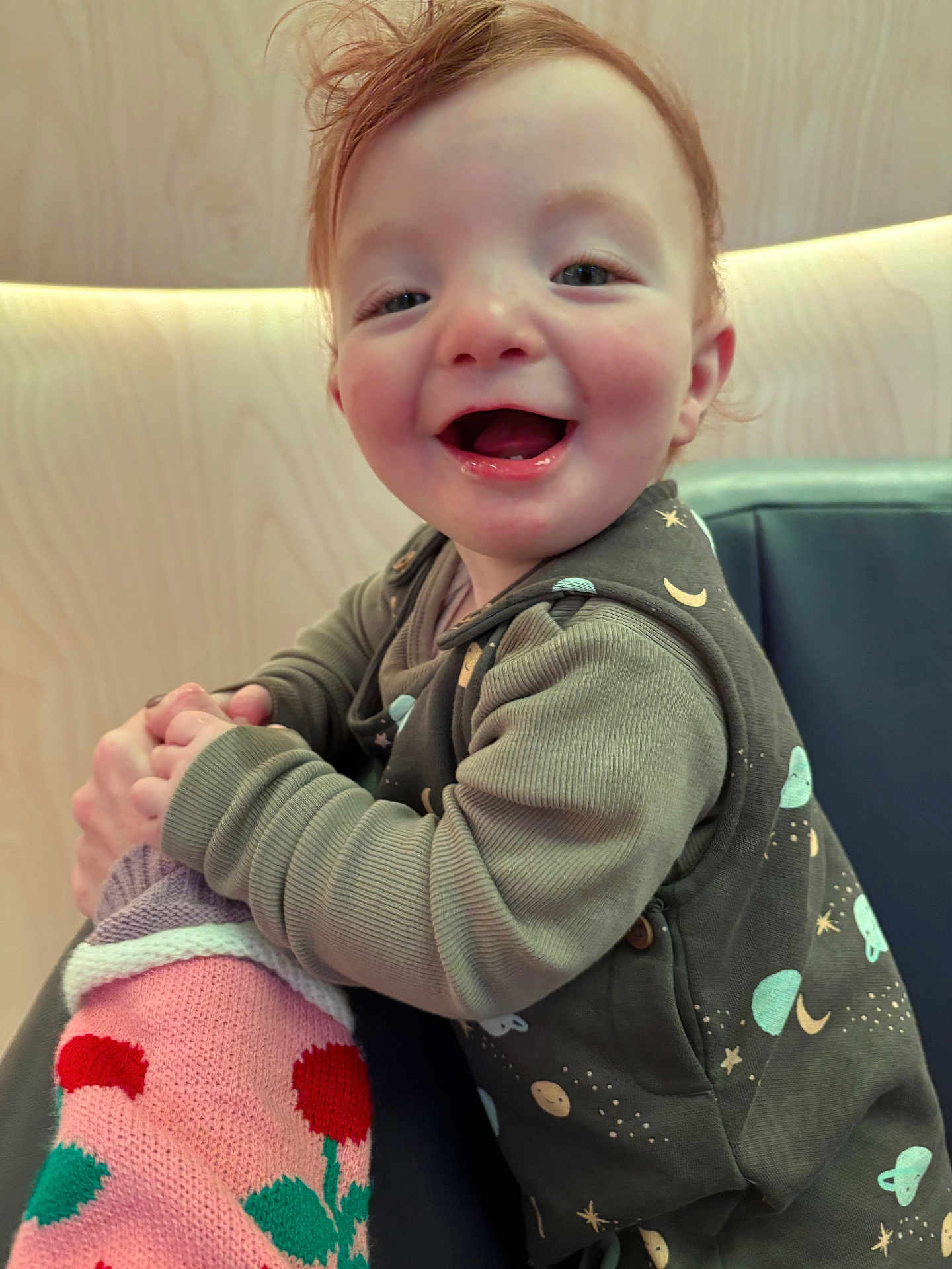 Donnie joined the competition — help win amazing prizes! toddler, child, smiling, happy, clothing, knitted_doll, indoor, face, person, sitting, plush_toy, long_sleeve, patterned_clothing, wood_background, cushion, cute, portrait, baby, playful, joyful