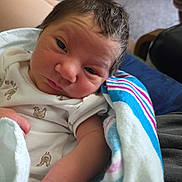 Azazel joined the competition — help win amazing prizes! newborn, baby, infant, blanket, striped_blanket, clothing, white_onesie, face, hair, arm, person, indoors, carpet, furniture, holding, resting, curious, closeup, skin, newborn_baby
