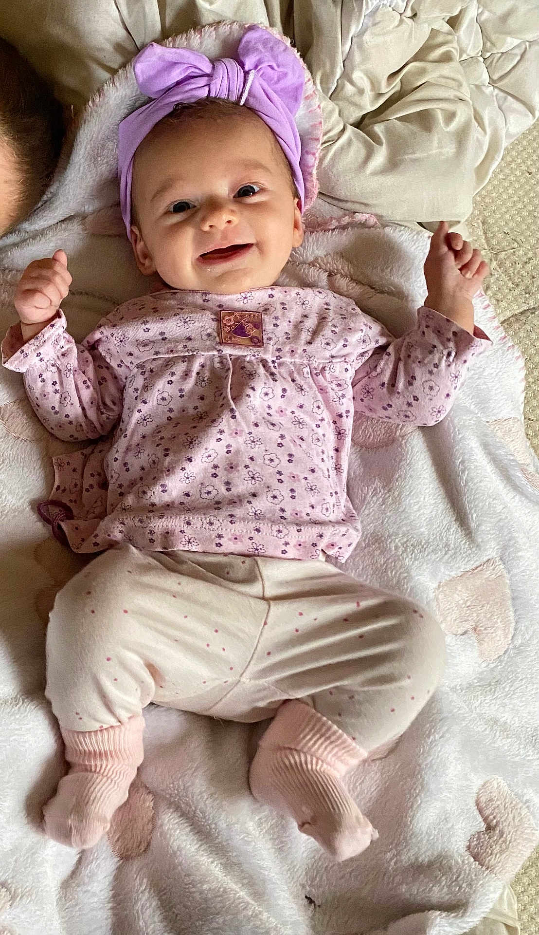 Margaux a rejoint le concours — aidez-le/la à gagner de superbes lots ! baby, smiling, headband, purple, pink, clothing, blanket, lying_down, happy, infant, cute, soft_texture, fabric, indoors, person, child, socks, sleepwear, portrait, cozy