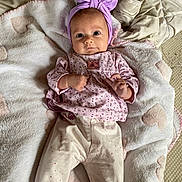 Margaux participe au concours pour gagner de l'argent avec cette photo : baby, infant, blanket, heart_pattern, headband, purple, pink_clothing, long_sleeve, pants, soft_texture, lying_down, indoors, curious_expression, small_hands, cute, cozy, sleepwear, person, portrait, child