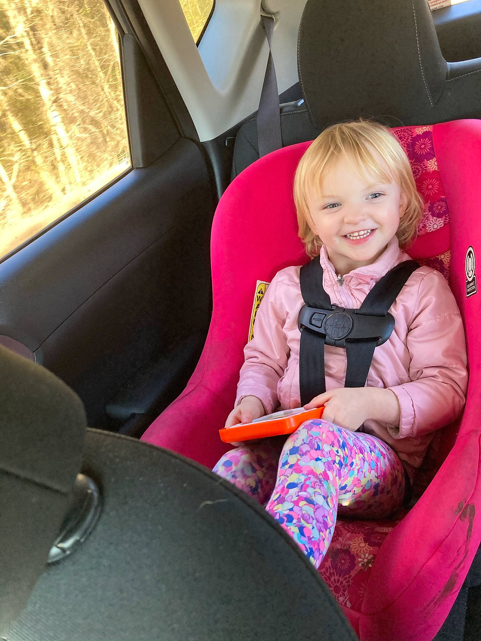 Chloie is registered to the contest to win money with this photo: auto_part, automotive_design, automotive_exterior, car, car_seat, car_seat_cover, comfort, face, family_car, head_restraint, joy, leisure, motor_vehicle, person, personal_luxury_car, smile, steering_part, steering_wheel, toddler, vehicle