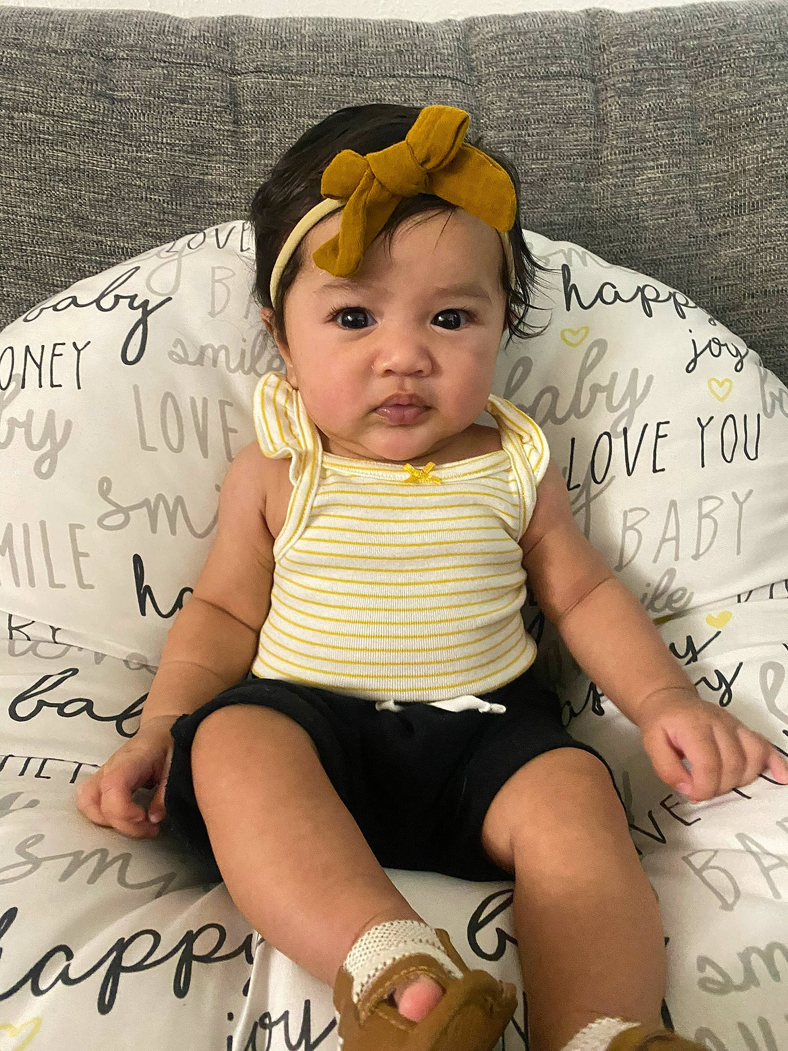 Micah is registered to the contest to win money with this photo: baby, baby_toddler_clothing, child, comfort, facial_expression, fashion_accessory, font, handwriting, happy, human_leg, knee, linens, pattern, person, pink, product, shorts, sitting, sleeve, thigh