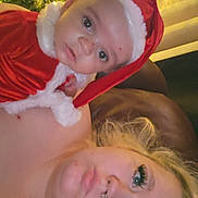 Christopher joined the competition — help win amazing prizes! baby, child, woman, santa_hat, christmas_tree, holiday, festive, lights, portrait, face, closeup, indoor, person, costume, red_clothing, blonde_hair, eyelashes, nose_ring, skin, celebration