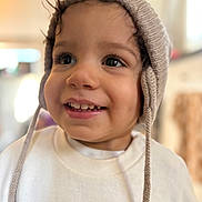 Cameron is registered to the contest to win money with this photo: toddler, child, smiling, hat, knit_hat, ear_flaps, sweatshirt, animal_print, cheetah, face, eyes, indoor, soft_light, portrait, happy, cute, young_child, clothing, closeup, person