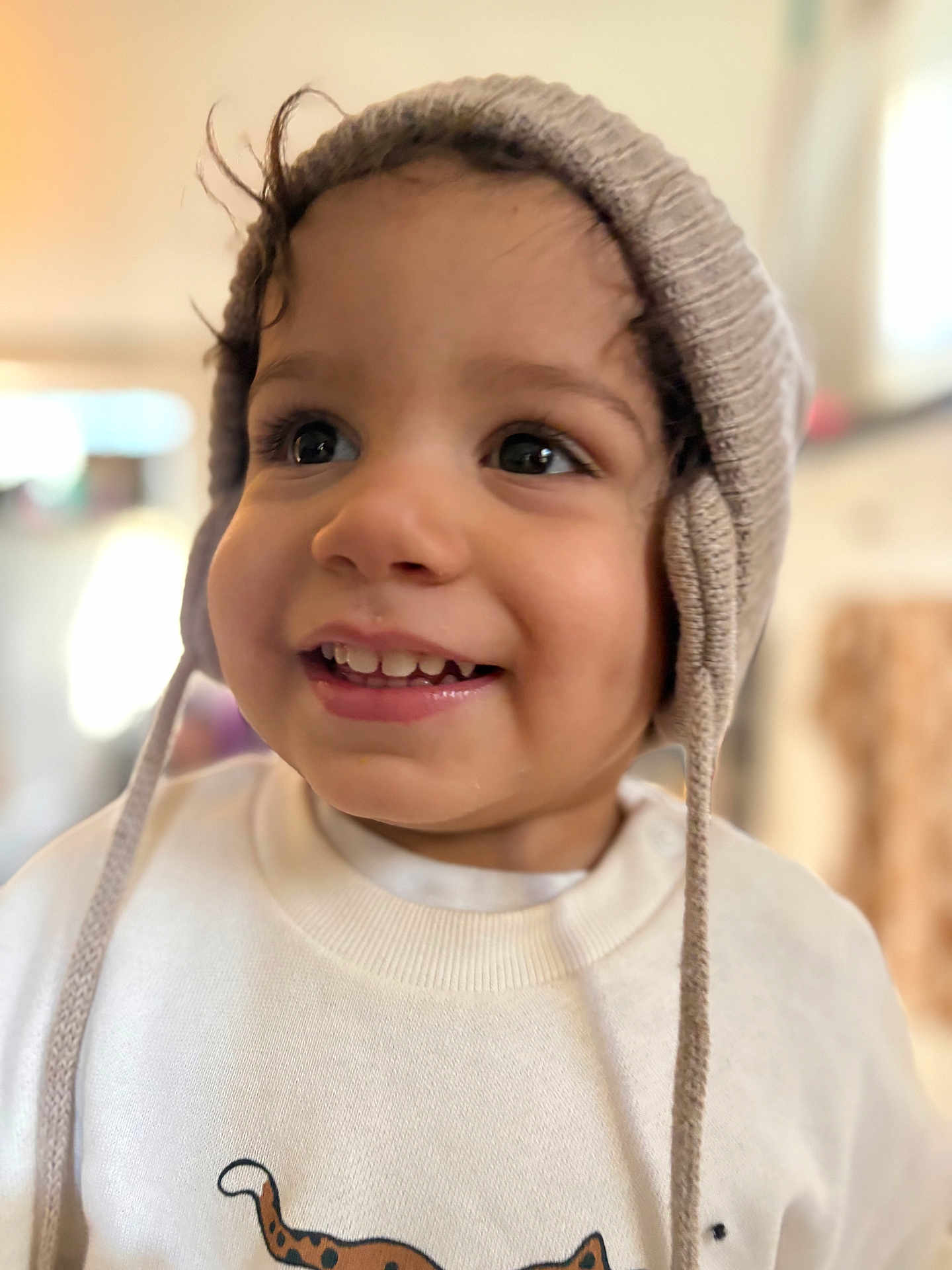 Cameron is registered to the contest to win money with this photo: toddler, child, smiling, hat, knit_hat, ear_flaps, sweatshirt, animal_print, cheetah, face, eyes, indoor, soft_light, portrait, happy, cute, young_child, clothing, closeup, person