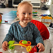 Preston a rejoint le concours — aidez-le/la à gagner de superbes lots ! toddler, child, walker, toy, smile, indoor, playtime, living_room, baby, happy, seat, clothing, floor, entertainment, furniture, television, playmat, plastic, red, blue