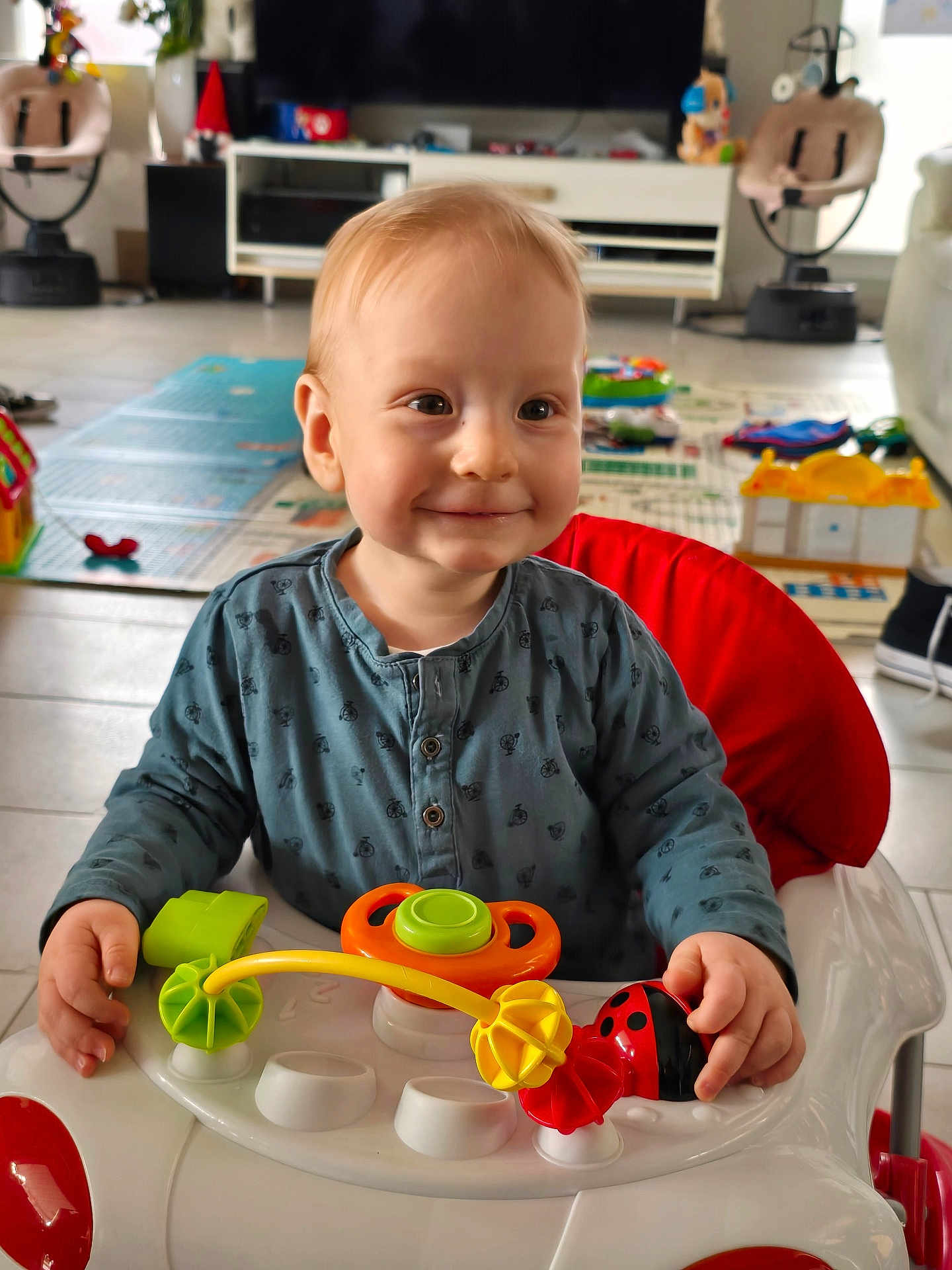 Preston a rejoint le concours — aidez-le/la à gagner de superbes lots ! toddler, child, walker, toy, smile, indoor, playtime, living_room, baby, happy, seat, clothing, floor, entertainment, furniture, television, playmat, plastic, red, blue